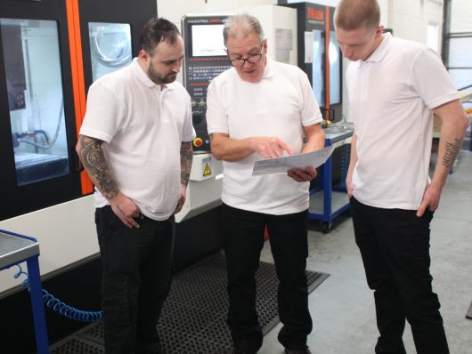 CNC staff training with operators beside a Mazak machine